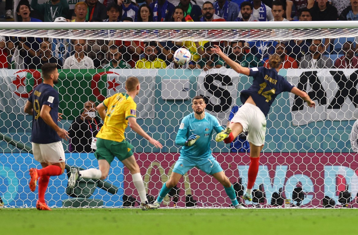 Goal keeper with legs wide, looking intently at the ball coming at him as Rabiot is in mid-air, with foot still in a kick and arms out