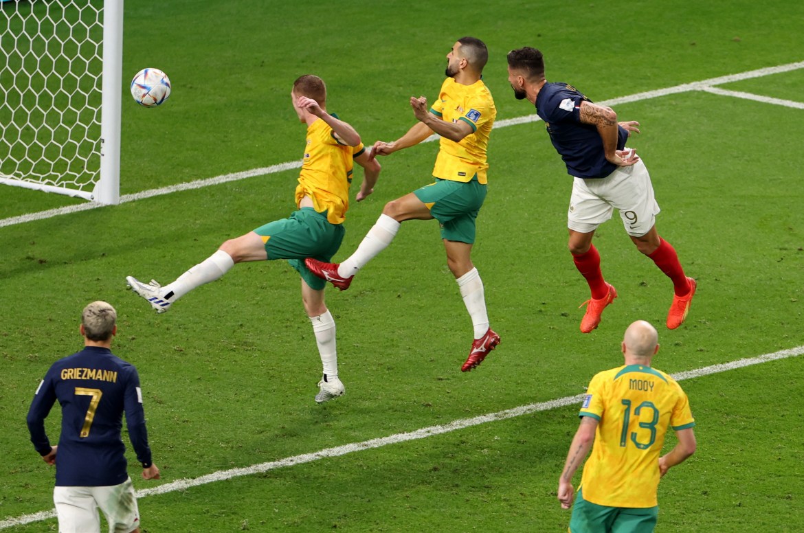 From the side and top, Giroud's left foot in a kick near the goal with the ball hovering above it, as several other players are in motion next to him