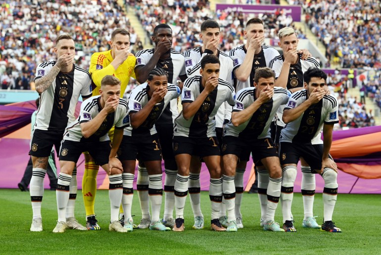 Germany players cover their mouths as they pose for a team group photo before the match against Japan.