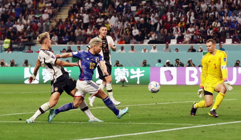Asano kicks the ball, while the goalkeeper bends down to block it