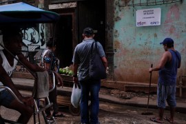 People buy vegetables next to a sign advertising upcoming elections, in Havana, Cuba
