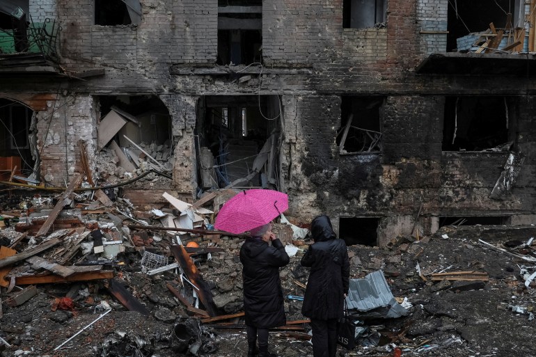 우크라이나 키예프 인근 비슈호로드 마을에서 러시아 미사일 공격으로 파괴된 건물 근처에 주민들이 서 있다.