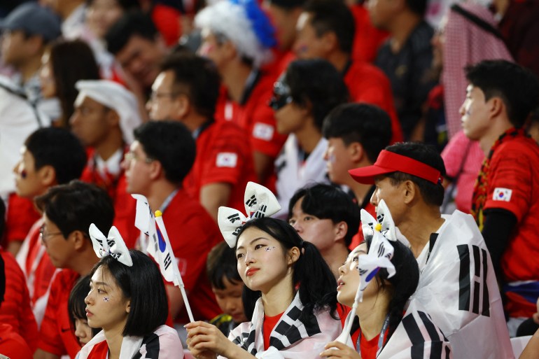韓國球迷揮舞著旗幟，頭髮上繫著絲帶