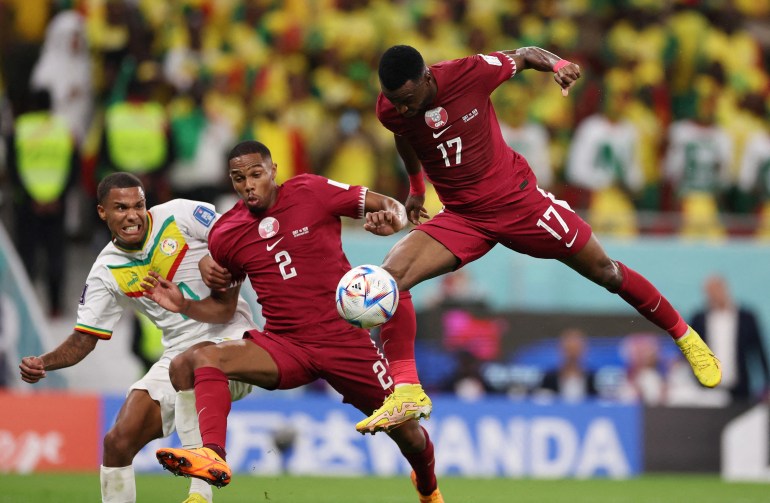 Ismail Mohamad of Qatar in the air with the ball as Pedro Miguel runs alongside and Ismail Jakobs of Senegal catching up behind him