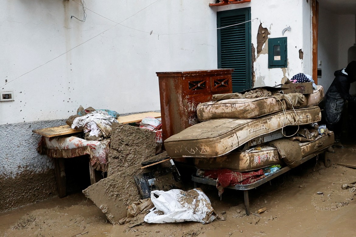 Residents' belongings covered in mud pile up outside a building