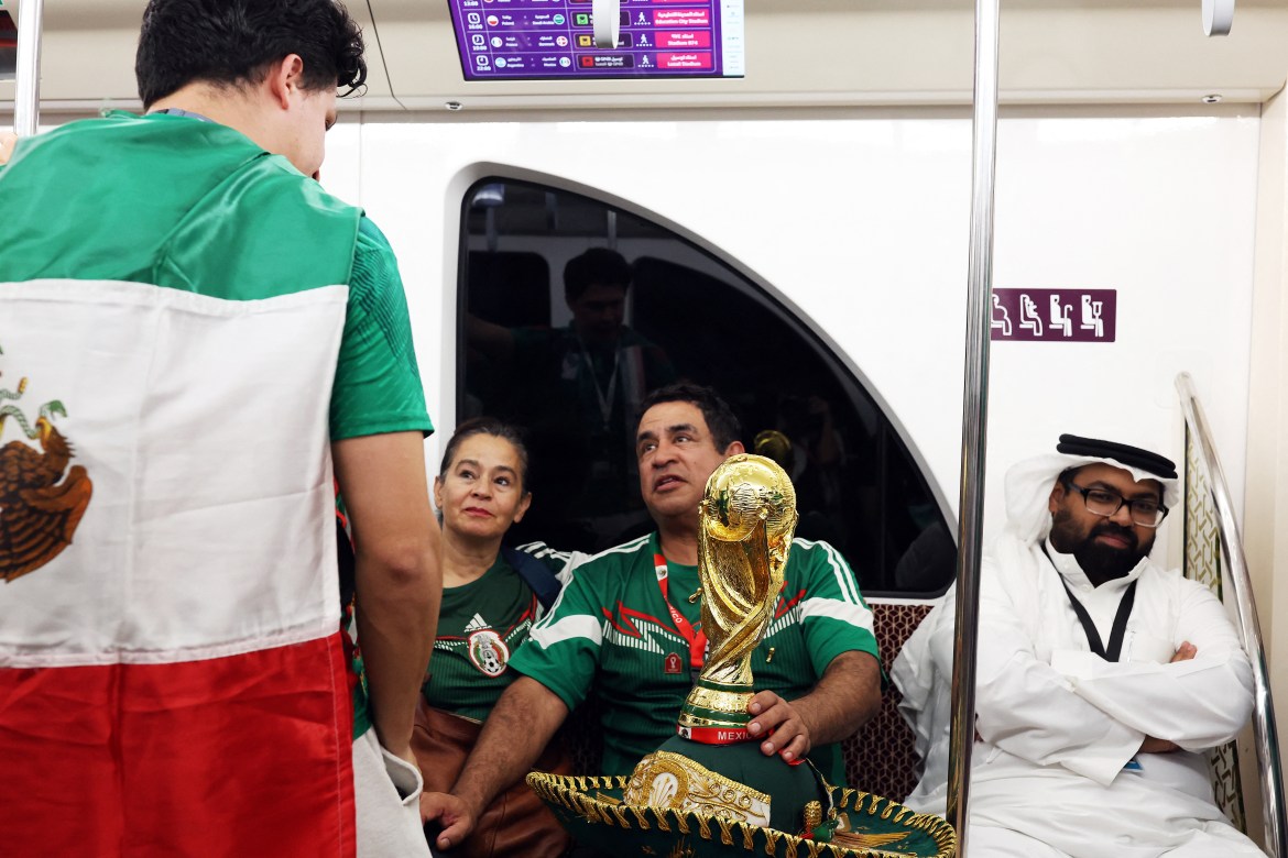 Mexica fans with a FIFA World Cup trophy replica are seen on the Doha Metro