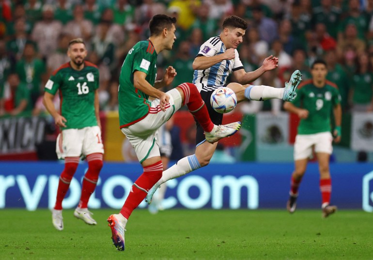 Argentina's Julian Alvarez jumps up to stop Mexico's Cesar Montes from getting control of the ball.