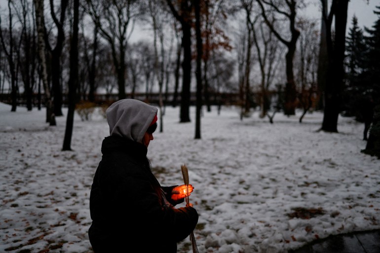 A woman holds a candle and ears of wheat as she visits a monument to Holodomor victims of the 1932-33 famine, in which millions died of hunger