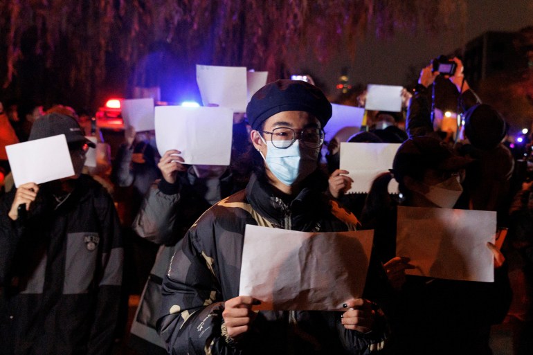 COVID-19 제한에 항의하기 위해 빈 종이를 들고 중국에서 마스크를 쓴 시위대.
