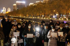 A crowd gathers at night in Beijing holding blank sheets of paper to show their anger over the COVID-19 lockdowns