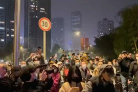 Masked people gather at a nighttime protest against COVID measures in Chengdu, China.