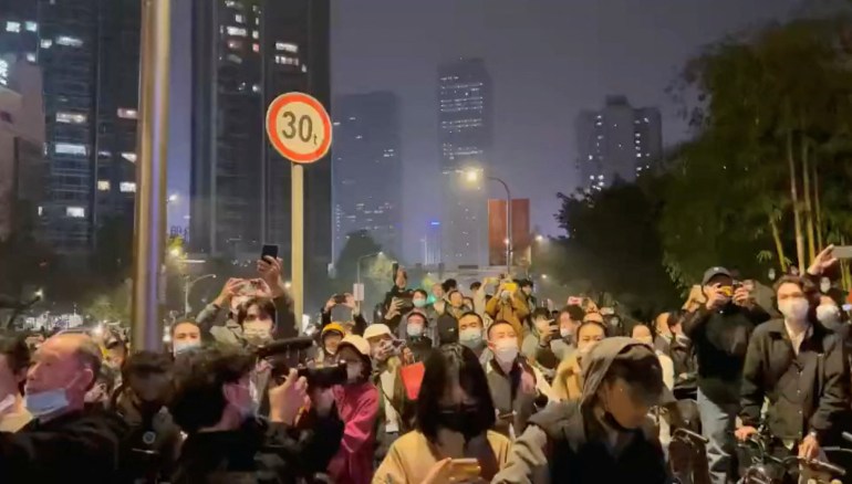 People wearing face masks gather during a nighttime protest against COVID-19 prevention measures in Chengdu, China.