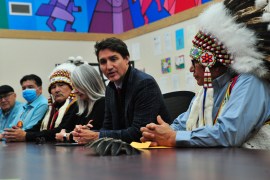 Indigenous leaders in James Smith Cree Nation sitting with Justin Trudeau at a long table.