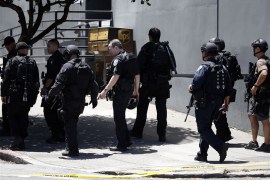San Francisco SWAT officers in front of a building where a shooting has taken place. They are in black military-like uniforms and carrying weapons