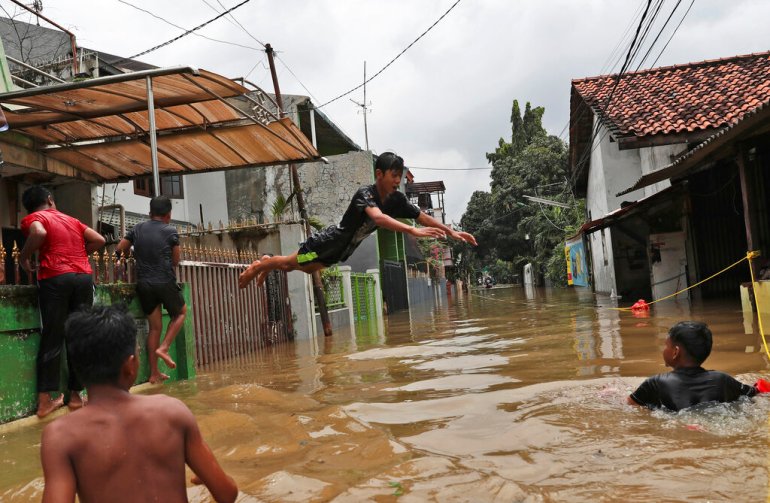 Indonesian youths play in flood water in a Jakarta neighbourhood.
