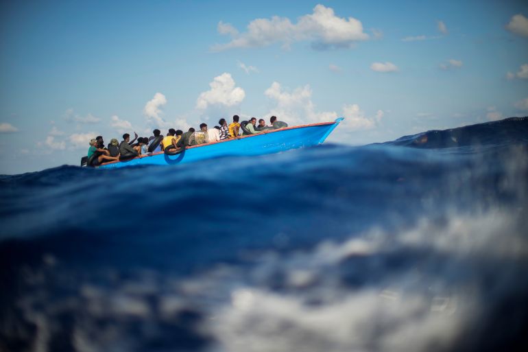 Migrants and refugees are seen on a wooden boat in the Mediterranean sea