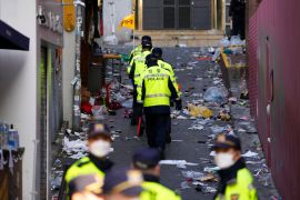 Police officers walking through a laneway with rubbish on the ground