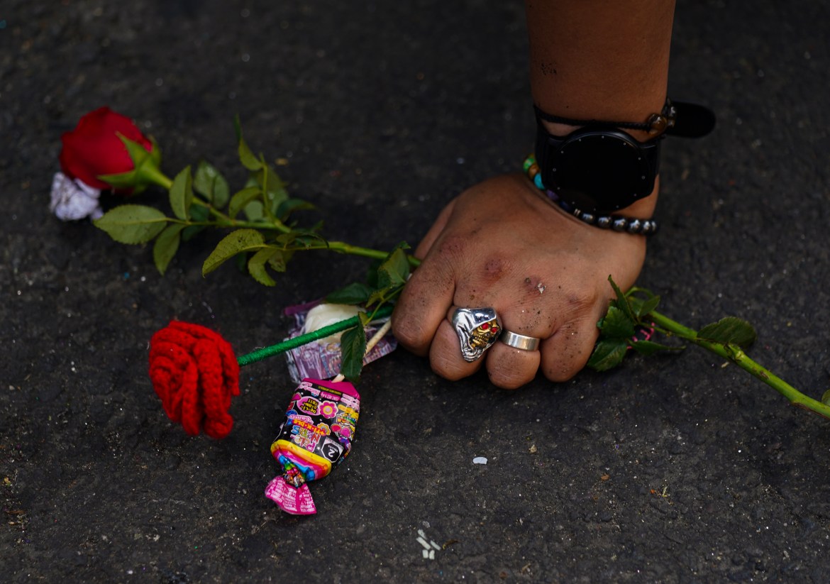 A woman's hand on the ground holding flowers.