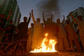 Supporters of former Pakistani Prime Minister Imran Khan's party, Pakistan Tehreek-e-Insaf, chant slogans next to a burning tire during a protest to condemn a shooting incident on their leader's convoy, in Karachi, Pakistan, Thursday, Nov. 3, 2022. A gunman opened fire Thursday at a campaign truck carrying Khan, wounding him slightly in the leg and killing one of his supporters, his party and police said. Nine others were also wounded. (AP Photo/Fareed Khan)