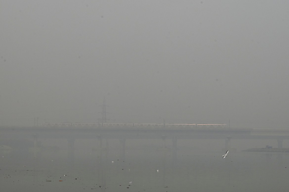A metro train runs on a bridge enveloped by smog and haze in New Delhi.