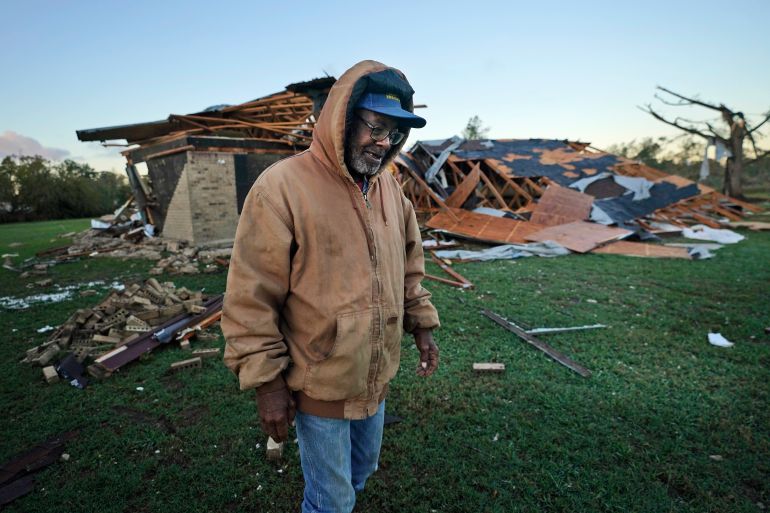 Willie Meeds walks from a relative's home, debris scattered all around, after helping turn off the houses water main following a tornado hit in Powderly, Texas.
