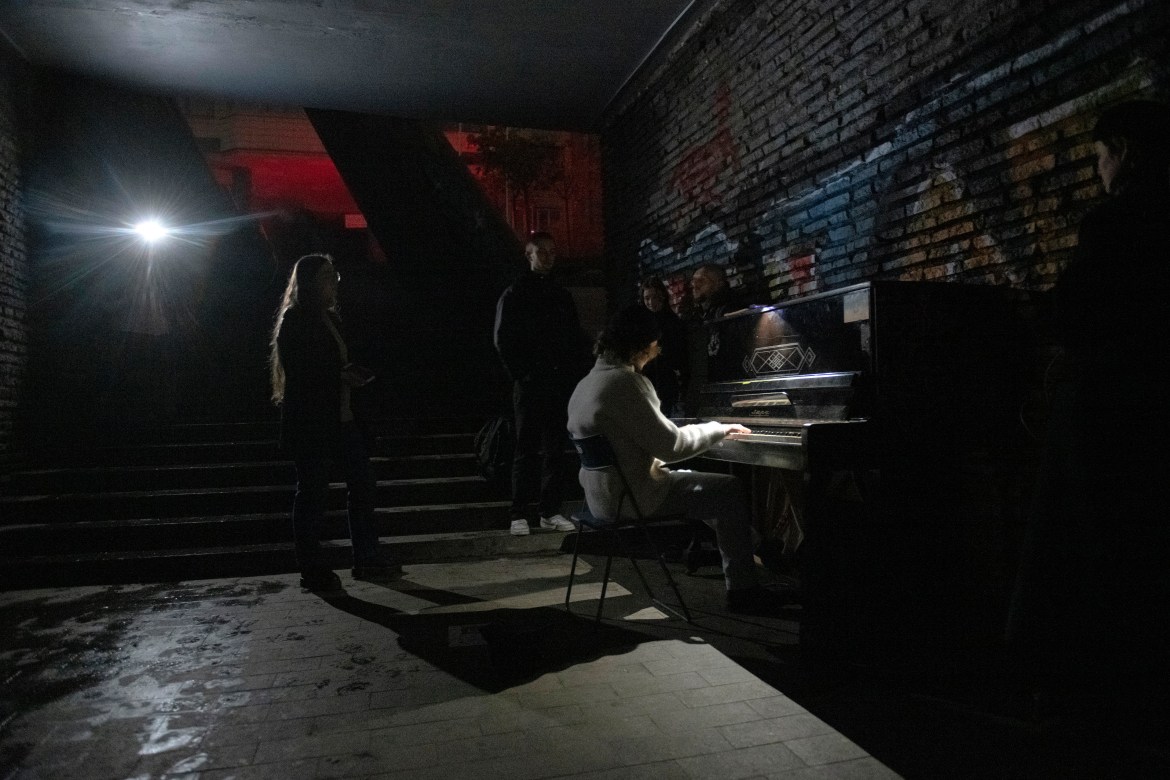 A person plays a piano in a street underpass during a blackout in Kyiv