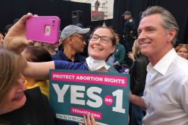 An abortion rights supporter takes a selfie with a "Yes on 1" sign and California governor Gavin Newsom.