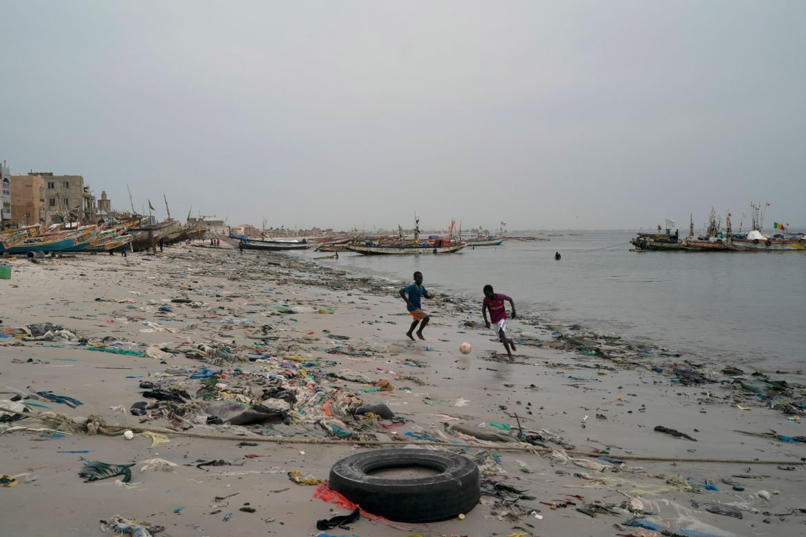 Boys play soccer among trash that litters the sand of Yarakh Beach in Dakar, Senegal.