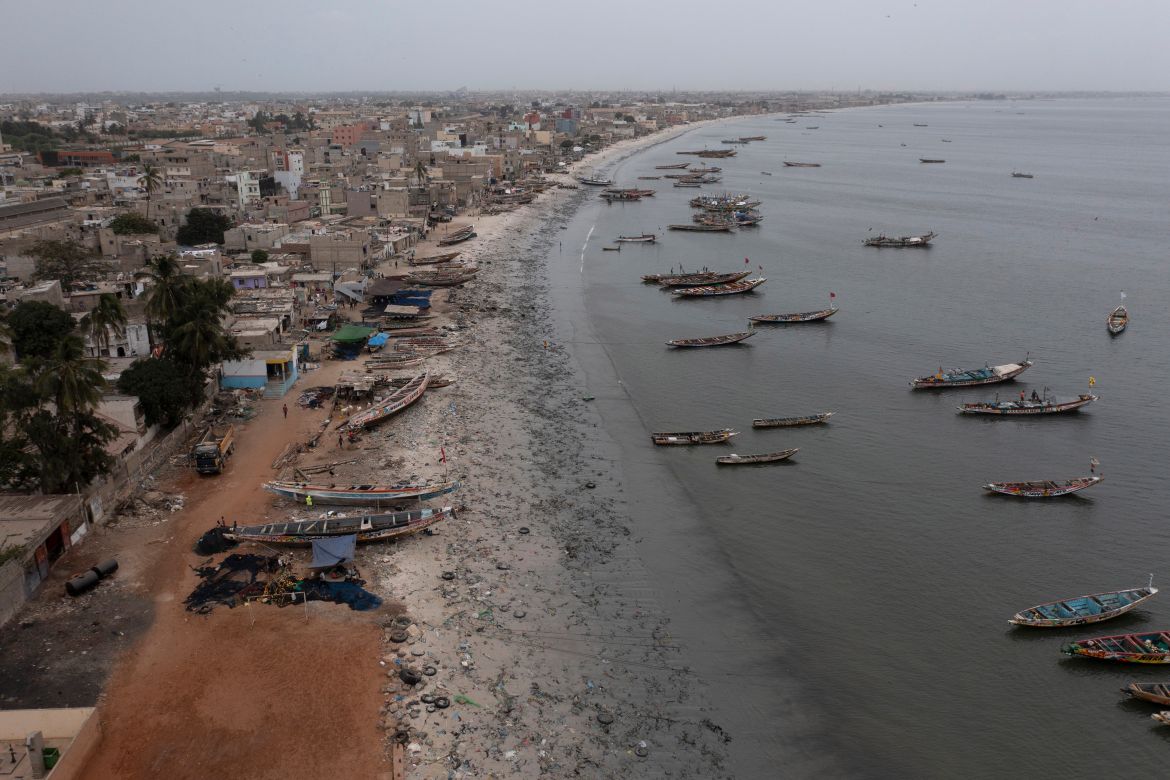 Traditional boats, known as pirogues, are docked at the Yarakh Beach littered by trash in Senega