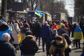People with Ukrainian flags walk towards Russian army trucks during a rally against the Russian occupation in Kherson on March 20