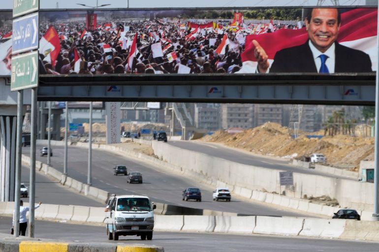 Vehicles drive under a giant billboard showing Egyptian President Abdel Fattah el-Sissi in Cairo.