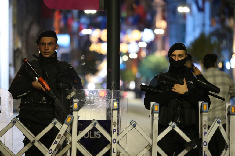 Police officers, carrying automatic rifles, stand at the entrance of the street after an explosion on Istanbul's popular pedestrian Istiklal Avenue.