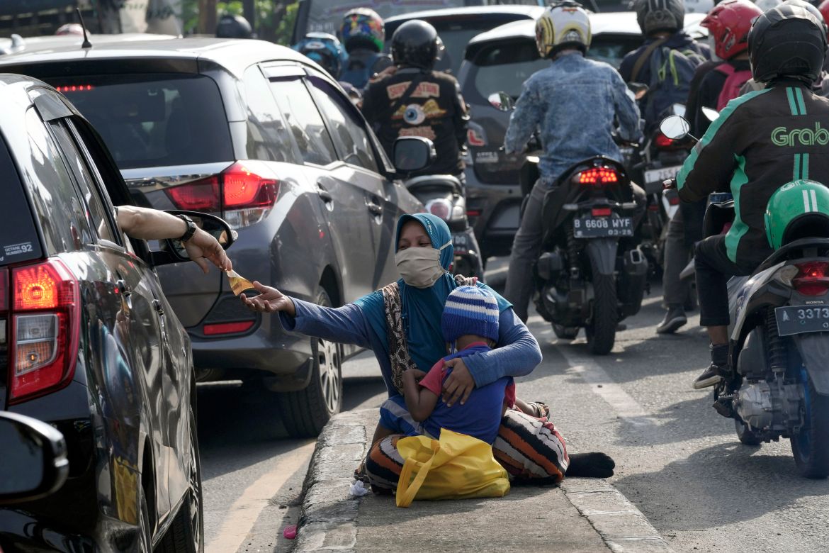 A motorist gives money to beggars while stuck in the morning rush hour traffic in Jakarta