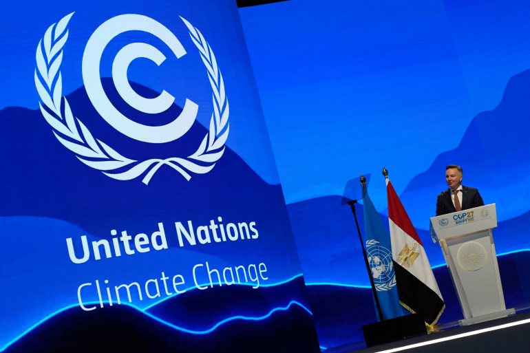 Australia's climate minister Christopher Bowen making a speech at COP27 against a bright blue backdrop showing the UN climate talks logo
