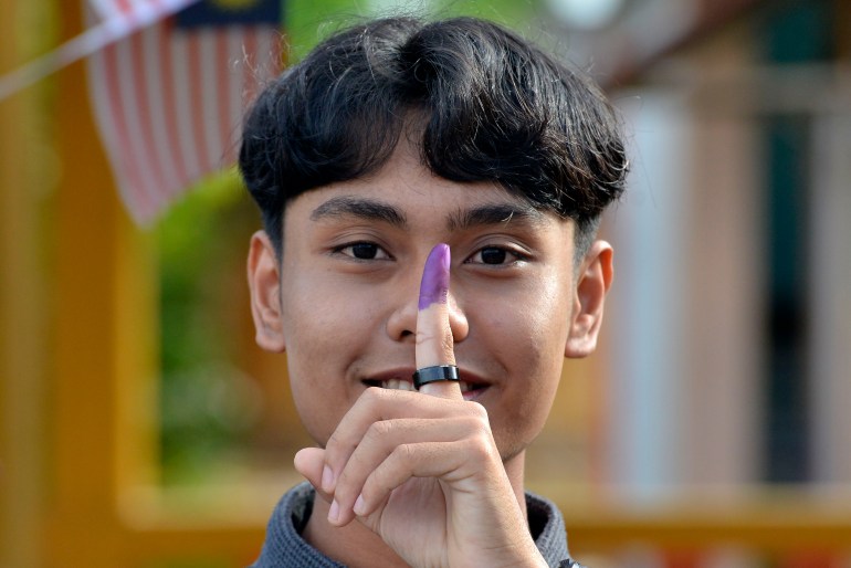 Genç bir erkek seçmen, Malezya'da oy kullandıktan sonra mürekkepli parmağını gösteriyor