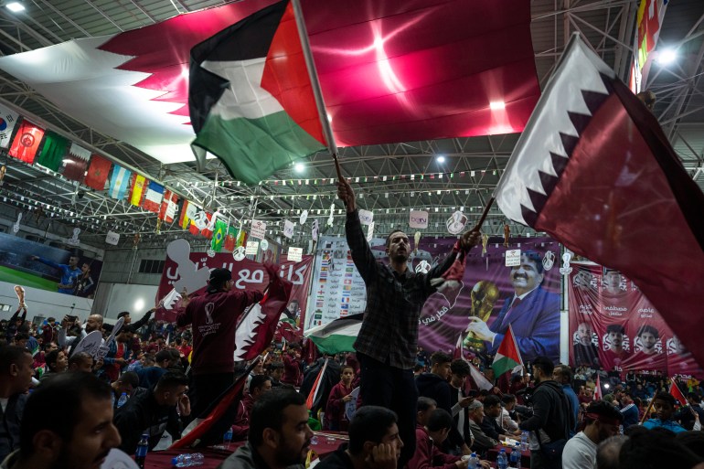 Palestinian football fans waving Qatari and Palestinian flags watch a live broadcast of 2022 World Cup opening match in occupied Gaza. 