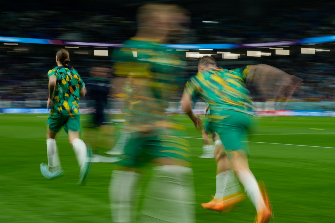 A motion blurred picture of three green-uniformed players from the back running onto the field