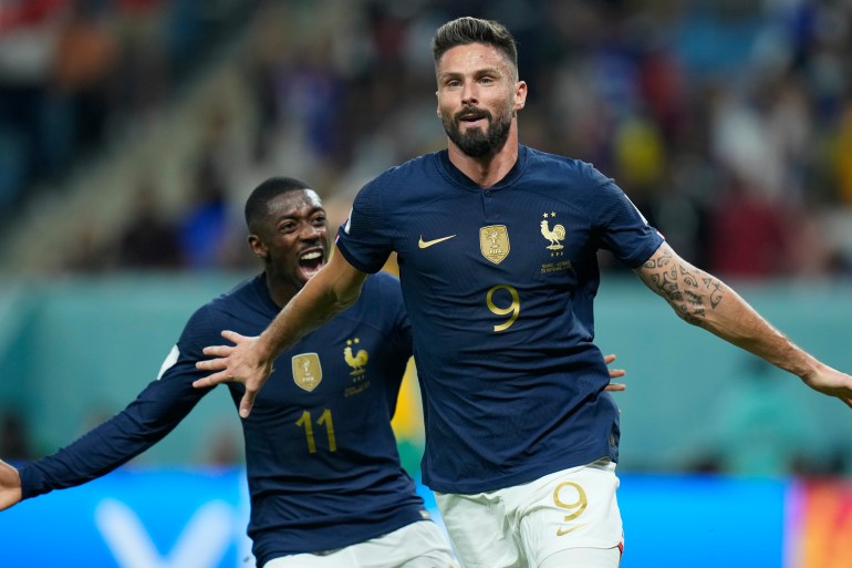 Giroud runs with his arms out as Dembele comes up behind him, smiling