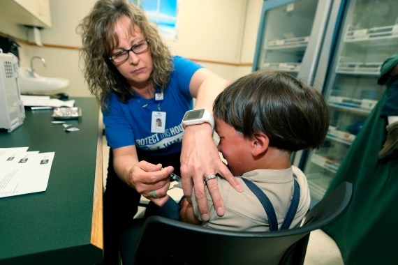 A young boy grimaces as a nurse gives him a measles vaccination