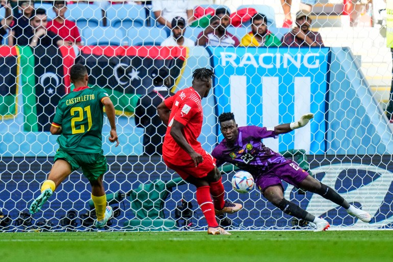 Embolo scoort zijn doelpunt voor Zwitserland met de Kameroense keeper die opzij springt om het te blokkeren