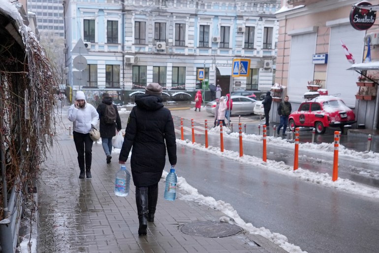 A Ukrainian employee of the Kiev Ministry of Health walks away after collecting rainwater from a drainpipe in Kiev.