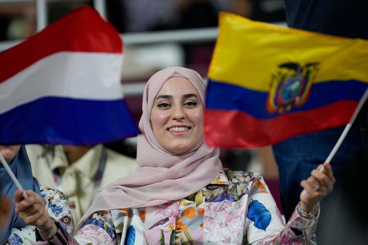 A woman holds the flags from Netherlands and Ecuador