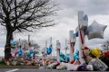 A woman ties balloons to a cross in a makeshift memorial to victims of a mass shooting at a Walmart in Virginia, US