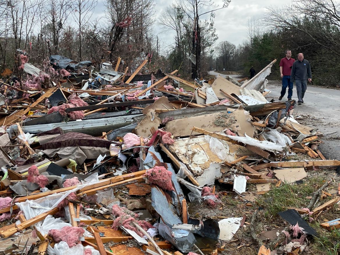 People walk through an area of destroyed structures in Flatwood, Ala