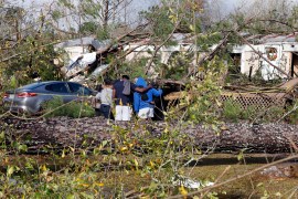 Friends and family pray outside a damaged mobile home on Wednesday, November 30, 2022 in Flatwood, Alabama, the day after a severe storm swept through the area. [Butch Dill/AP Photo]