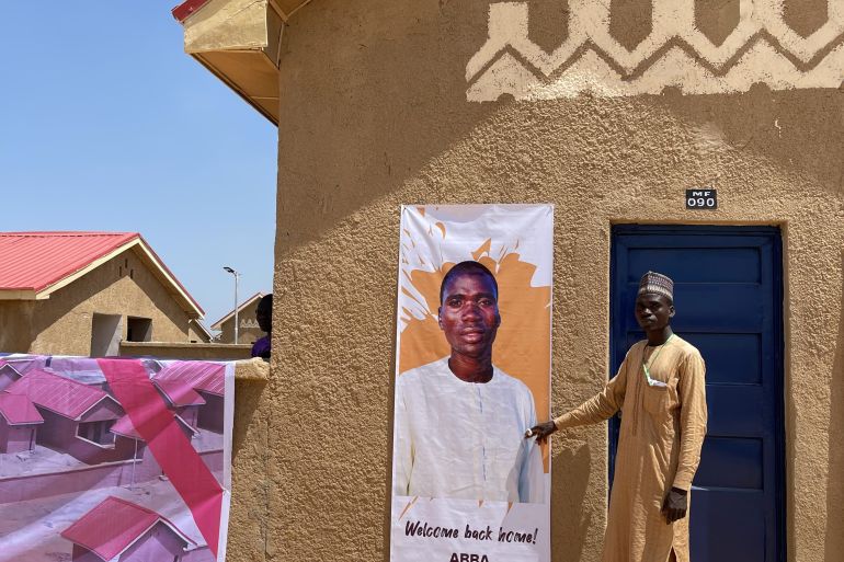 Saleh Abba stands in front of his new house in Ngarannam, Borno [Festus Iyorah/Al Jazeera]