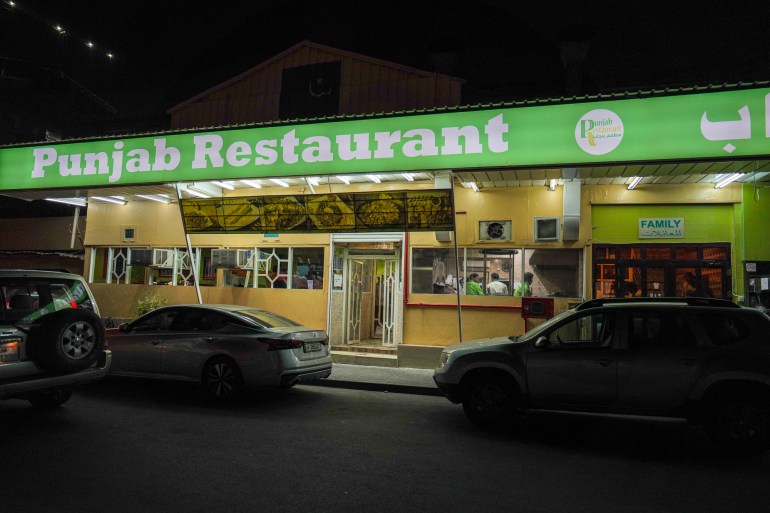 A view of the exterior of the old Punjab Restaurant at night, with a green sign running across the squat building