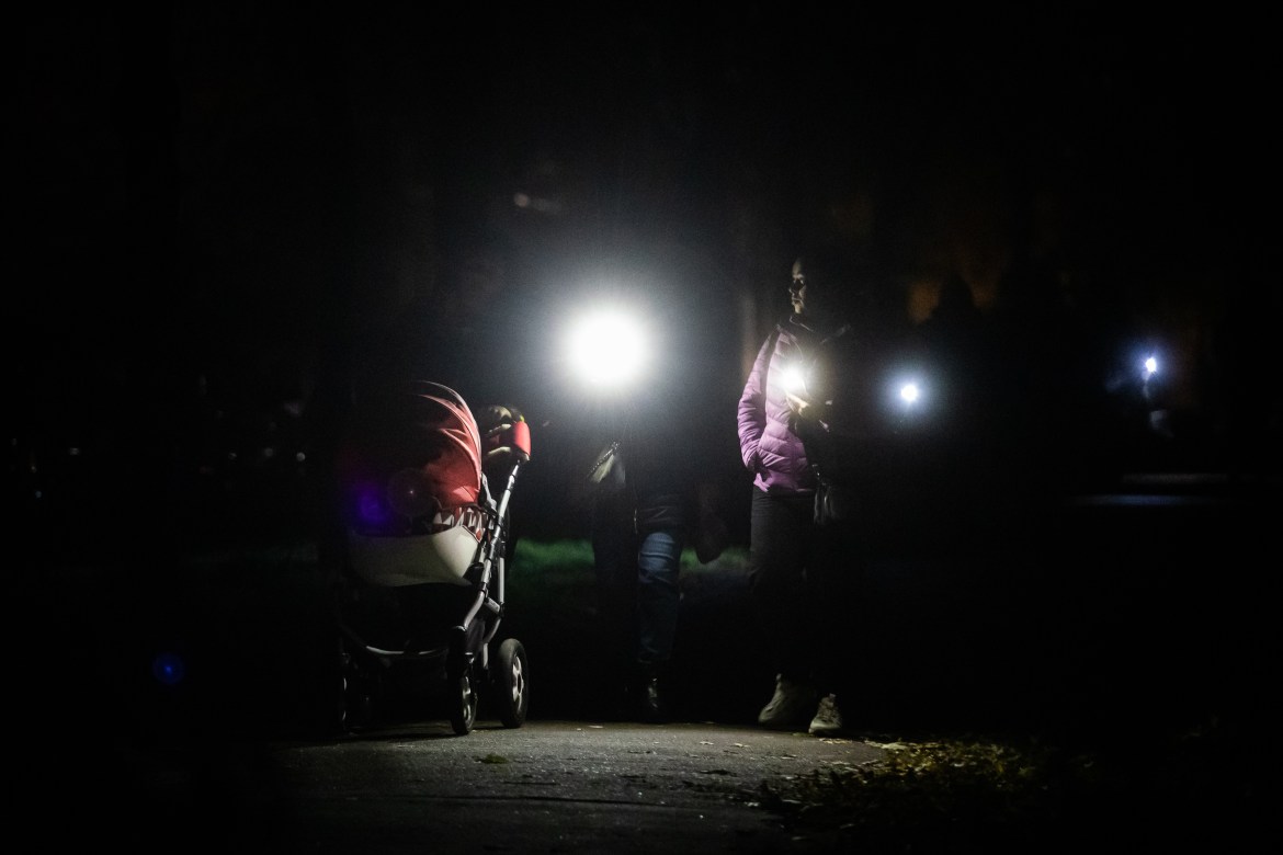 Residents of the residential district of Troieshchyna illuminate their way with flashlights of phones during an emergency blackout