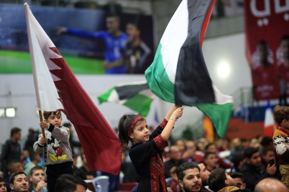 A girl waves a Qatari flag.