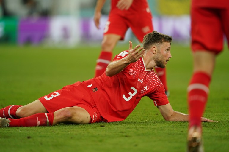 Swiss defender Silvan Widmer, splayed out on the pitch, looks to the referee.